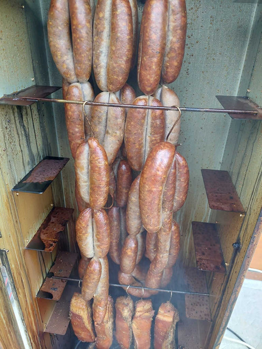 Saucisses artisanales fumées suspendues dans un fumoir, prêtes à être dégustées en cuisine traditionnelle.