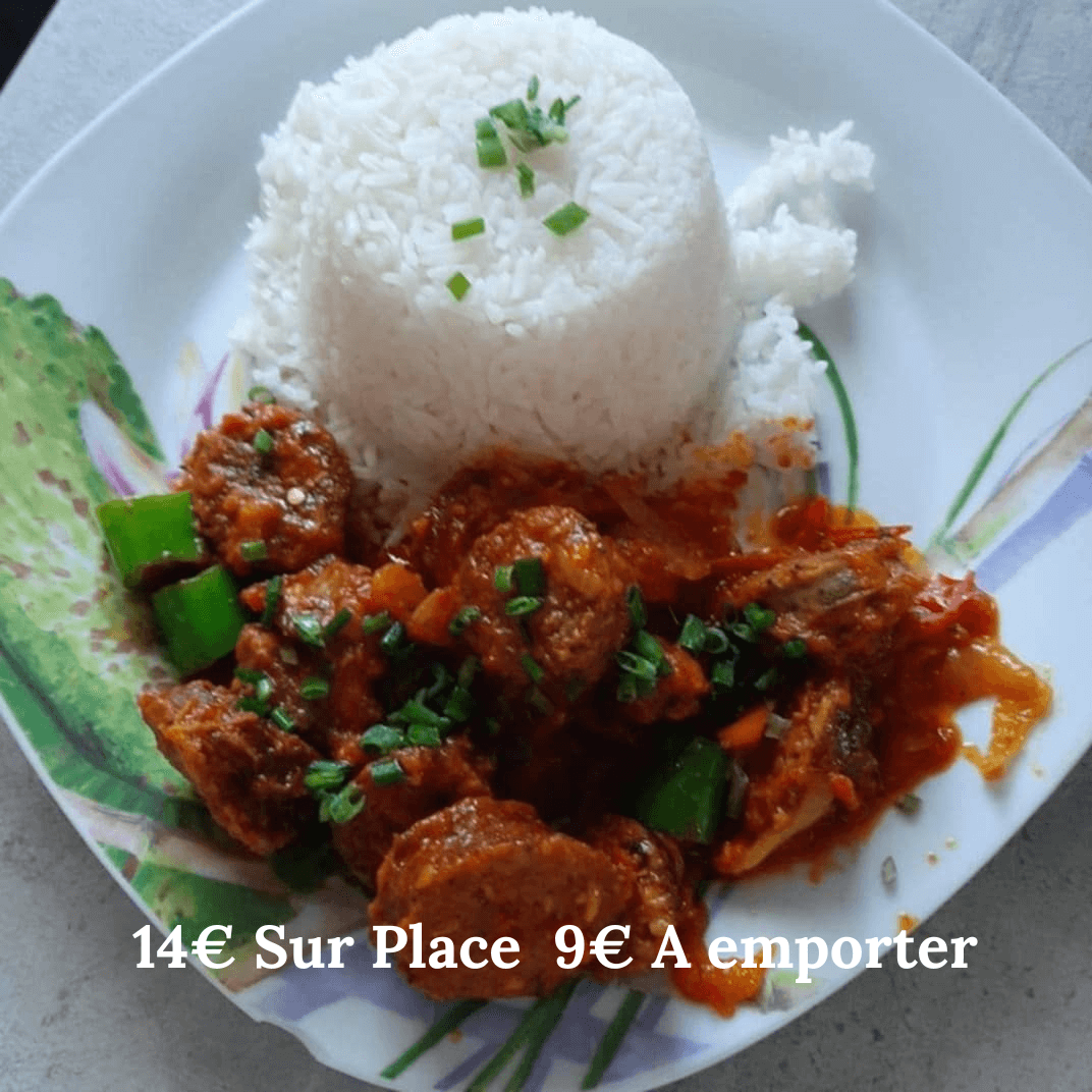 Plate of Rougail Saucisse with rice, garnished with green peppers and herbs, showcasing a delicious meal.